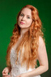 Beautiful red-haired young woman on a bright emerald green background