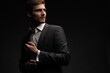 © opolja - Portrait of handsome man in black suit on dark background.