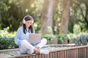 A content young woman enjoys learning on her laptop outdoors, surrounded by nature