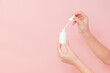 © Antonio - Hand holding glass cosmetic bottle for serum (hyaluronic acid and collagen) on pink background. Beauty concept