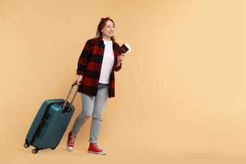 Sticker - Happy young woman with passport, ticket and suitcase on beige background, space for text