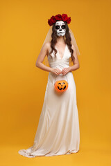 Poster - Young woman in scary bride costume with sugar skull makeup, flower crown on orange background. Halloween celebration