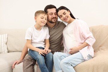 Wall Mural - Happy pregnant woman spending time with her son and husband at home