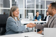 © New Africa - Lawyer shaking hands with client at table in office, selective focus