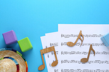 Sticker - Baby songs. Music sheets, wooden notes, cubes and hat on light blue background, flat lay