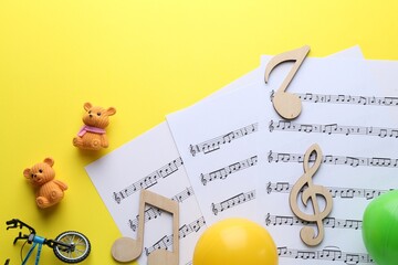 Sticker - Baby songs. Music sheets, wooden notes and different toys on yellow background, flat lay