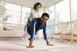 Happy strong athletic Indian dad piggybacking little daughter, keeping static yoga plank on floor, doing pushups with kids weight, looking at camera, exercising for strength, training body