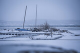 Fototapeta Do pokoju - A few old sail boats sit at a l lake covered by ice in the middle of winter off Stockholm, Sweden. 