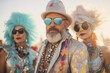 summer festival senior participants in desert with fancy costume one man two ladies, sunglasses, serious face fashion blue-dyed hair hats jewels fun party exuberant flamboyant bright carnival