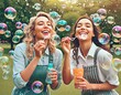 Happy women have fun playing a game of blowing bubbles in a park in summertime