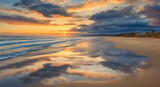 Fototapeta Zachód słońca - Reflection of clouds in coastal sand on the ocean shore at sunset