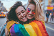 © Kordiush - Joyful Embrace in Rainbow Colors. Two happy women hugging, one wrapped in a rainbow flag, on a city street