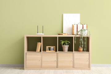 Poster - Chest of drawers with wi-fi router, plants and books near green wall in room