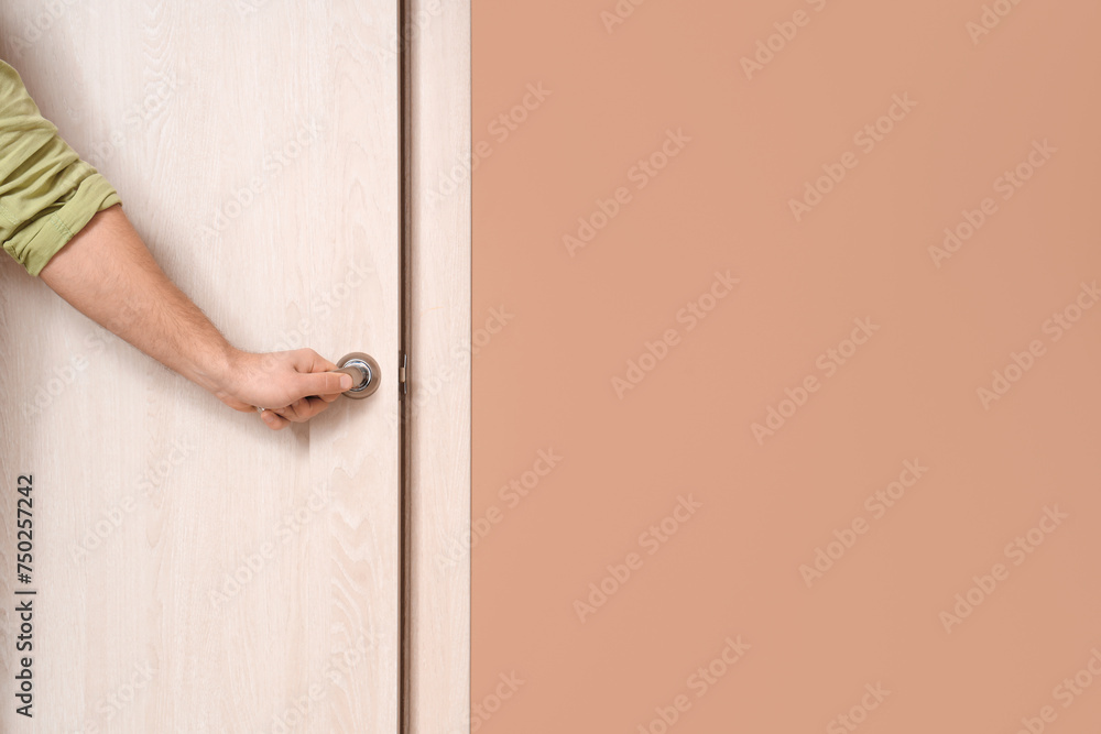 Young man opening wooden door at home, closeup