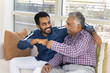 © fizkes - Happy joyful Indian young adult child man and senior father making fist bump friends gesture, expressing support, unity, respect, enjoying close family relationship, friendship