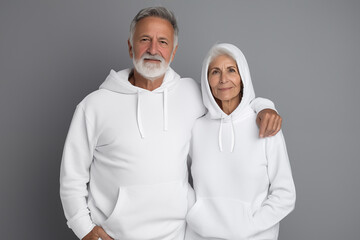 Wall Mural - Elderly couple in white hoodie on grey background for clothing mockup