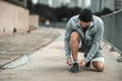 © Charnchai saeheng - A man tying shoelaces on sport shoes in the city center park before cardio workout, running.  Health and Lifestyle in big city life concept.