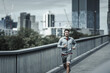 © Charnchai saeheng - A man running up on footbridge in the city center park for cardio workout.  Health and Lifestyle in big city life concept.