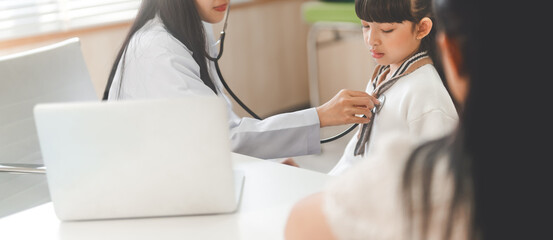 Wall Mural - Southeast asian doctor woman using stethoscope check little girl health care in kid clinic examining room