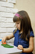 A 4-year-old girl plays with bright green glitter slime. This activity promotes the development of fine motor skills, creative thinking and imagination.