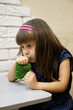 A 4-year-old girl plays with bright green glitter slime. This activity promotes the development of fine motor skills, creative thinking and imagination.