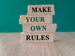 Make your own rules symbol. Concept green words Make your own rules on brick blocks. Beautiful wooden table, green background. Business motivational make your own rules concept.