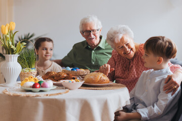 Grandparents with grandchildren eating traditional easter lunch. Recreating family traditions and customs. Happy easter.