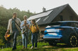 © Halfpoint - Family with electric car in front house with solar panels on roof. Solar, green energy and sustainable lifestyle of young family.