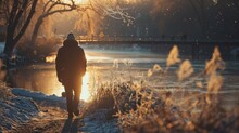 Person walking alone on snowy path during sunset. Winter landscape with golden light and snowflakes. Solitude and winter season concept. Design for poster, banner, and seasonal themes with copy space