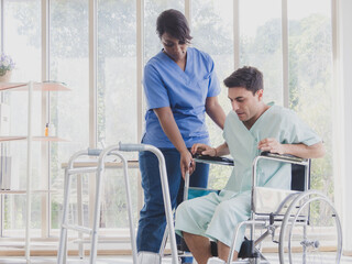 Portrait patient caucasian man sit wheelchair with woman nurse carer physical therapist African-American two people talk helping support give advice feel relax smile happy in hospital room service.