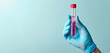 The simplicity of a blood vial in a clinical glove contrasts with the plain blue backdrop, signifying cleanliness