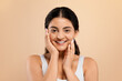 © Prostock-studio - Portrait of joyful indian woman in white top touching cheeks with hands
