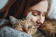 © ADDICTIVE STOCK - Woman affectionately cuddling with her sleeping cat. Generative AI image