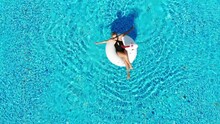  Woman Relaxing In Pool Float Unicorn Inflatable Ring Floating On Turquoise Pool Water. Aerial Top View From Drone.