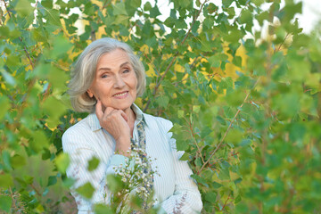 Wall Mural - Portrait of happy senior woman posing at forest