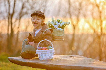 Wall Mural - Beautiful stylish toddler child, boy, playing with Easter decoration in the park, springtime