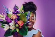 © Dulúapics - Afro-American woman excited to receive a beautiful bouquet of flowers on Mother's Day against a purple background