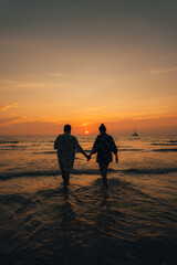 Wall Mural - Summer sunset,Couple walking on the beach watching the sunset