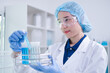 © Supapich - Closeup female woman scientist's hand holding blue liquid chemical chemistry test tube working in analyze science laboratory research experiment