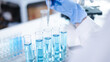 © Supapich - Close-up hands dropping fluid from dropper flask beaker into blue test tube sample laboratory for compare in medicine chemical biology medical science experiment technology biotechnology analysis