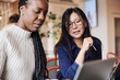 © Maskot - Businesswoman discussing with female colleague over laptop at coworking office