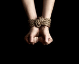 Fototapeta  - Hostage hands tied with a rope over black background