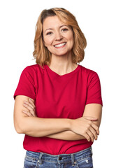 Blonde middle-aged Caucasian woman in studio who feels confident, crossing arms with determination.