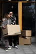 © Maskot - Smiling man embracing woman holding box while standing in front of apartment
