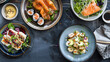 A variety of sushi, including nigiri and sashimi, artistically presented on dark ceramic plates, ready to serve