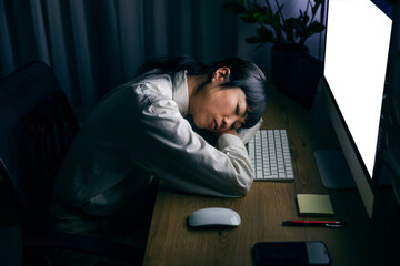 A tired asian businesswoman is sleeping at her home office late at night.