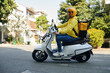 © DragonImages - Side view of young man working as courier riding on motorcycle