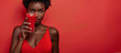 Dark skinned woman holding red smoothie or other red vegetable smoothie wearing red. Concept of healthy eating and healthy food. Banner whit copy space in red background