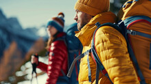 A man in a yellow jacket and a woman in a red jacket are standing on a snowy mountain