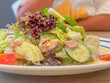 Closeup of salad with tuna meat and vegetables in white plate on wooden table